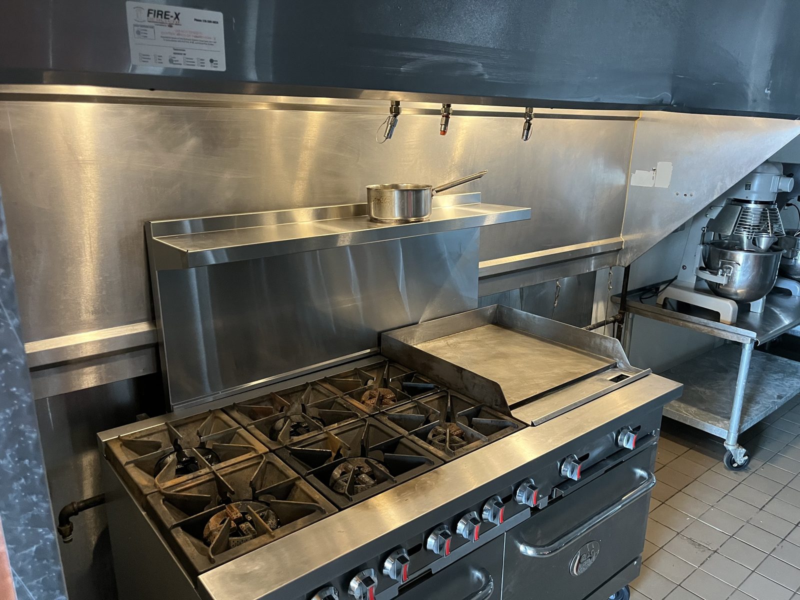 Six-burner range with griddle and oven beneath the hood